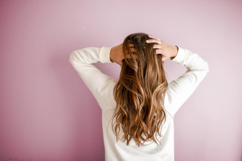 Loose, sunlit waves against a dusty rose wall
